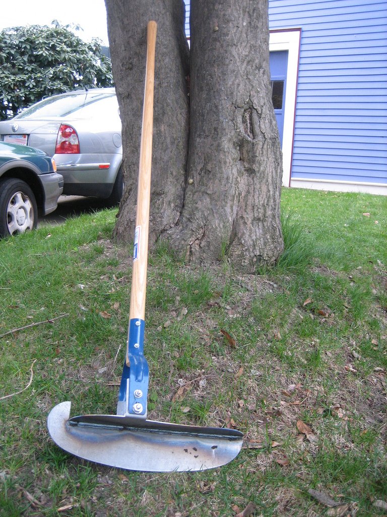 Manueller Rasenkantenstecher mit Holzstiel auf einer Rasenflaeche